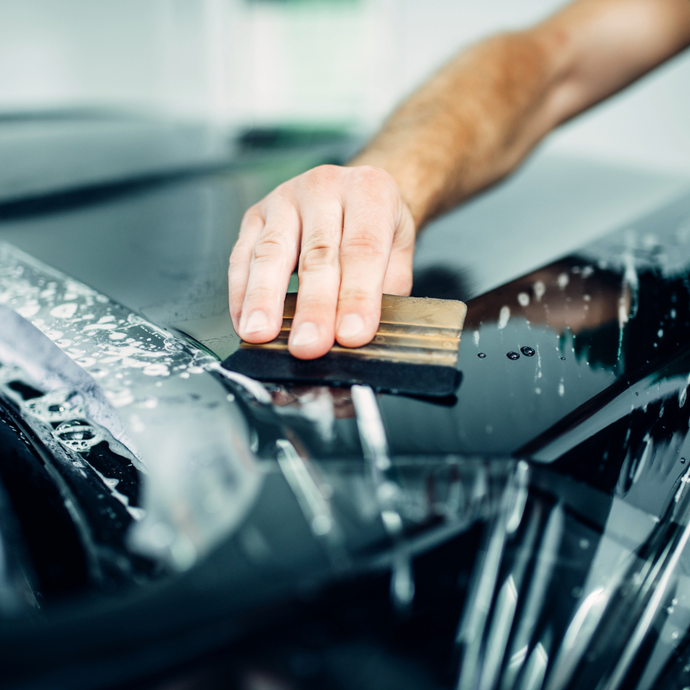 A worker installing film paint protection on a car