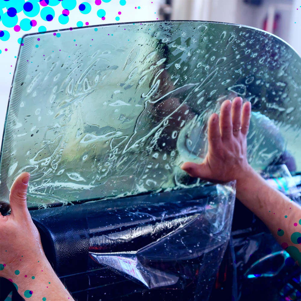 A worker applying window tint to a car